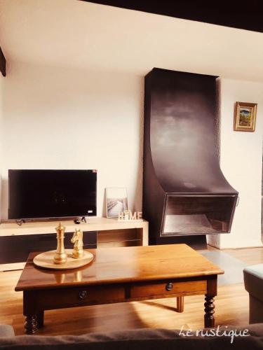 Una sala de estar con una mesa de café y un televisor de pantalla plana. en Le Rustique Apartement, en Morteau