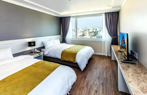 a hotel room with two beds and a window at Galaxy Hotel in Jeju