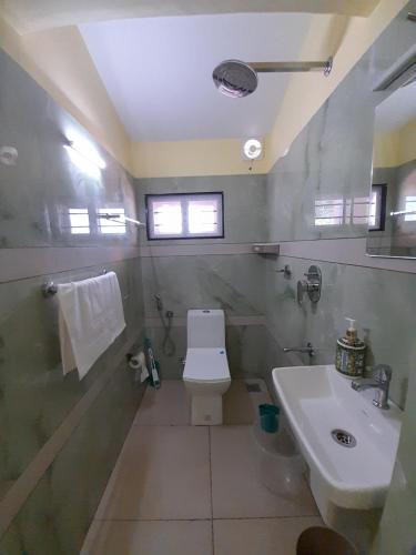 a bathroom with a white toilet and a sink at Majestic Serviced Villa in Kottayam