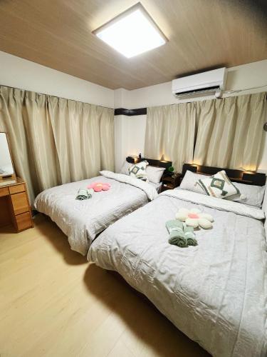 two beds in a hotel room with white sheets at 子安居 Koyasui in Yokohama