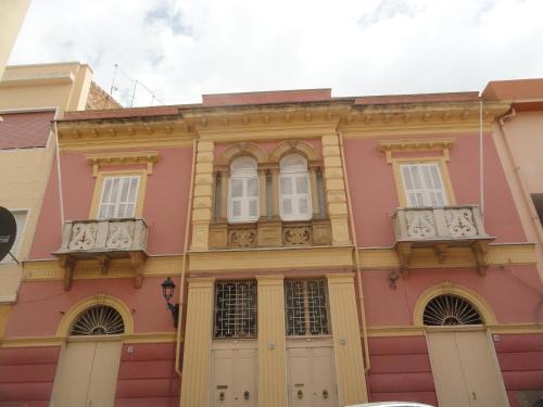 un edificio rosa con puertas y ventanas blancas en Casa Tonina, en Carloforte