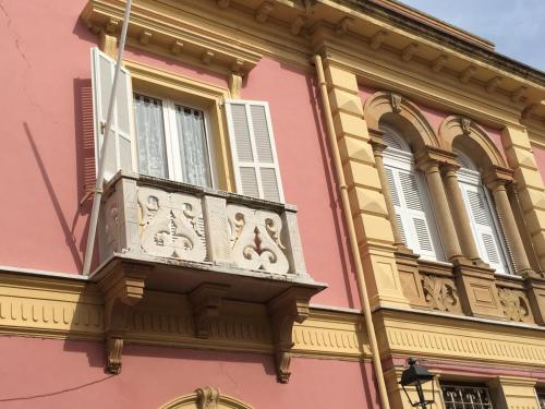 Edificio rosa y amarillo con balcón en Casa Tonina, en Carloforte