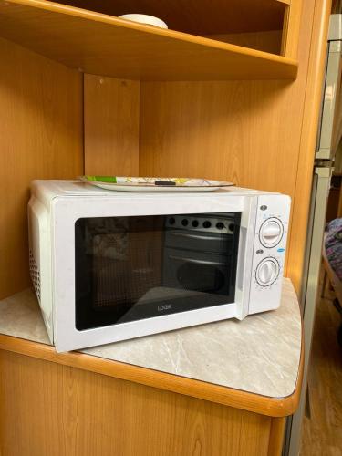 a white microwave sitting on top of a shelf at Tornio caravan in Tornio