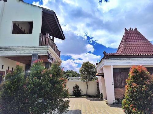 a white house with a roof and a building at Benada Piyungan Yogyakarta by ABM in Yogyakarta