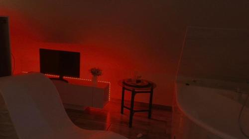 a red room with a tub and a tv and a table at FLÓRA VENDÉGHÁZ A BALATONNÁL in Lovas