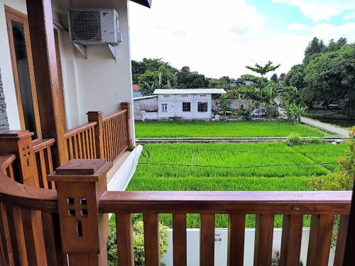 a wooden porch with a view of a rice field at Benada Piyungan Yogyakarta by ABM in Yogyakarta