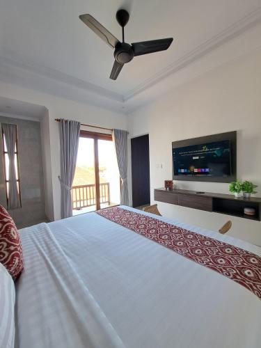 a bedroom with a large white bed with a flat screen tv at Paddy Villa Sanur in Sanur