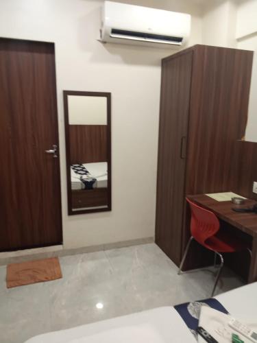 a room with a desk and a mirror and a cabinet at Best Hotel in Mumbai