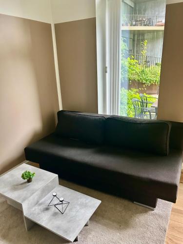 a black couch sitting next to a window with a table at New copy apartment at Aarhus Ø in Aarhus