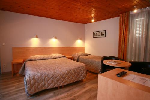 a hotel room with two beds and a table at Hôtel Panoramic in Luchon