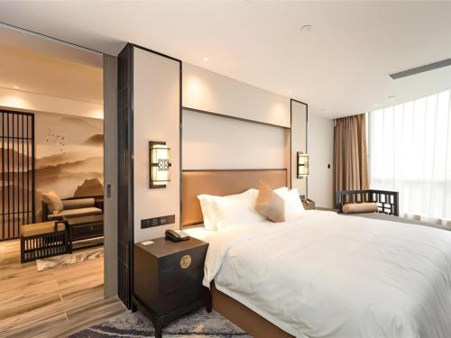 a bedroom with a large bed and a living room at Yuan Culture Hotel Shenzhen World Shajing in Shenzhen