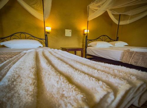 a bedroom with two beds with white blankets at Babai Outback Adventures PVT LTD in Bardia
