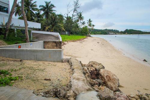 a sandy beach with a building and the water at Playa Del Pedro Beach House in Guam