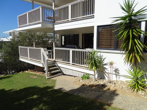 a house with two decks and a palm tree at Pandanus Palms Holiday Resort in Point Lookout