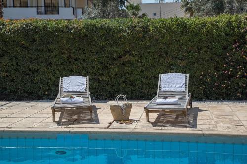 two lawn chairs sitting next to a swimming pool at Paphos Love Shack apartment in Paphos City