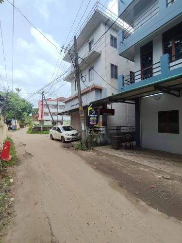 a white car parked in front of a building at Queens INN in Kodungallūr