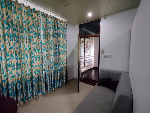 a room with a couch and a curtain with a window at Queens INN in Kodungallūr