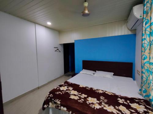 a bedroom with a bed with a blue headboard at Queens INN in Kodungallūr