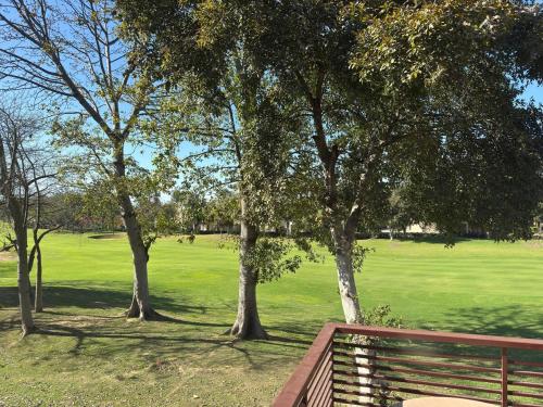 a bench in a park with trees and a field at Mor Pur - Royal Golf Course Stay in Manesar
