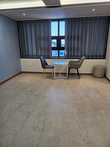 a room with two chairs and a table in front of a window at White Windmill Guesthouse in Mokpo