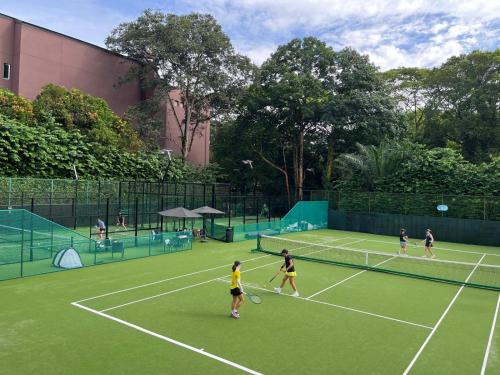 un grupo de personas jugando al tenis en una pista de tenis en Hollandse Club Resort, en Singapur