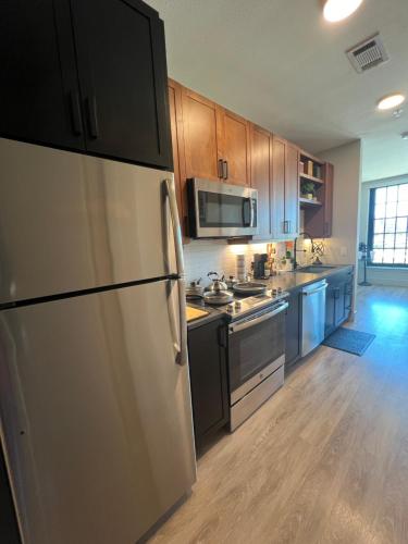 a kitchen with stainless steel appliances and wooden cabinets at Deep Ellum Theatre Suite - The Black Collection in Dallas