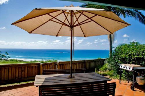 a wooden table with an umbrella on a patio at Pandanus Palms Holiday Resort in Point Lookout