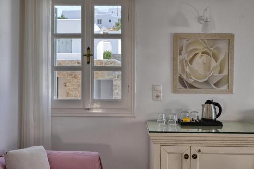 a room with a window with a flower on a counter at Paolas Sunset in Agios Stefanos