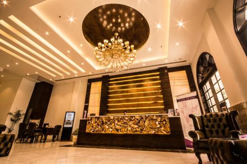 a lobby with a chandelier and a table and chairs at Regenta Central Amritsar in Amritsar