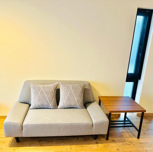 a couch with two pillows sitting next to a table at TIME SHARING STAY Ikebukuro in Tokyo