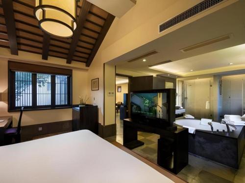 a bedroom with a tv and a bed and a mirror at Hotel Dayu Kaiyuan in Shaoxing