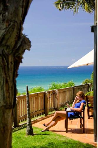 a woman sitting in a chair talking on a cell phone at Pandanus Palms Holiday Resort in Point Lookout