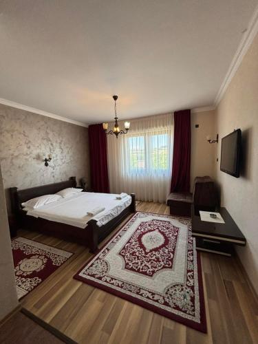 a bedroom with a bed and a table and a television at Hotel Ulpiana, Ethno House in Gracanica