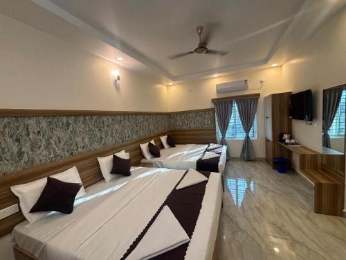 Un dormitorio con dos camas y un televisor. en Vainavi Residency, en Tirupati