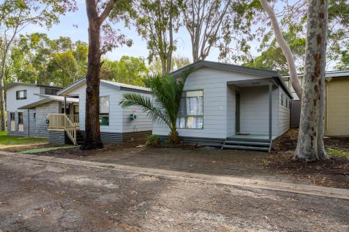a white house with trees in front of it at Kalganyi Holiday Park in Mount Gambier