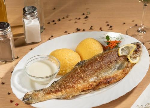 a plate with a fish and lemons on a table at Casa Izvorul Rece in Hobiţa
