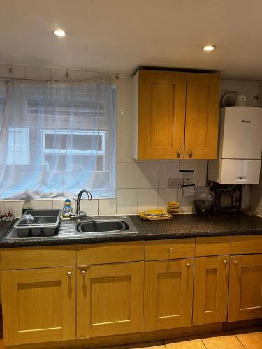 a kitchen with wooden cabinets and a sink and a window at close to stadium and the beach 2 bed groundfloor,sky Netflix in Grimsby