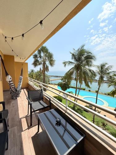 a balcony with a view of a pool and palm trees at Premium Lecheria - Oceanfront, Pool & Relax in Morro de Barcelona