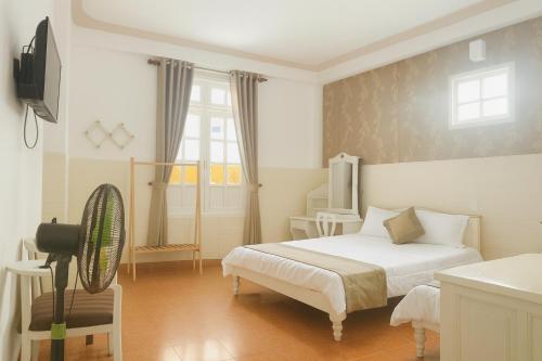 a bedroom with a bed and a television and a chair at LE VU HOTEl in Da Lat