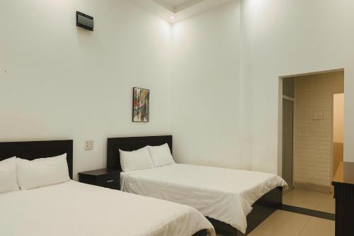 two beds in a room with white walls at LE VU HOTEl in Da Lat