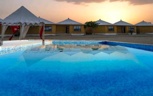 a large blue swimming pool in front of a building at Khamma Ghani Resort with pool Luxury camp in Jaisalmer in Jaisalmer