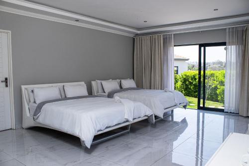 2 camas en un dormitorio blanco con una ventana grande en Louisville Resort, en Midrand
