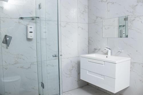 Un baño blanco con lavabo y ducha. en Louisville Resort, en Midrand