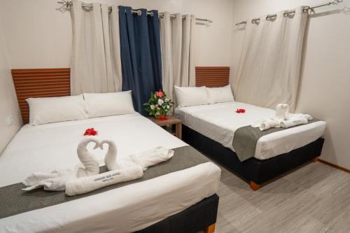 two beds in a room with swans towels on them at Airport Ace Villas in Nadi
