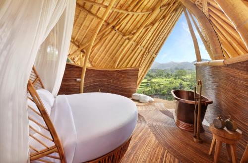 a room with a white chair and a window at Eden Villa by SARAYA Bali in Silebeng
