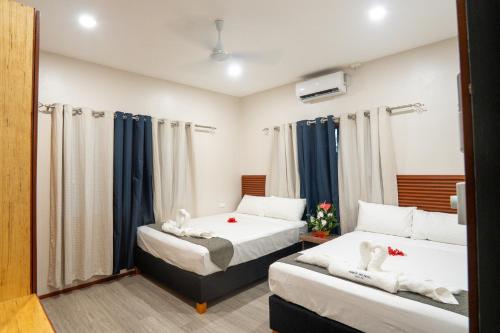 two beds in a room with blue curtains at Airport Ace Villas in Nadi