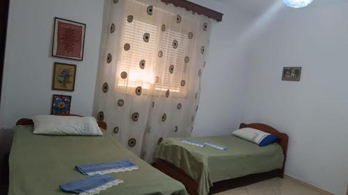 2 camas en una habitación con cortina y ventana en Kappa Guest House, en Fier