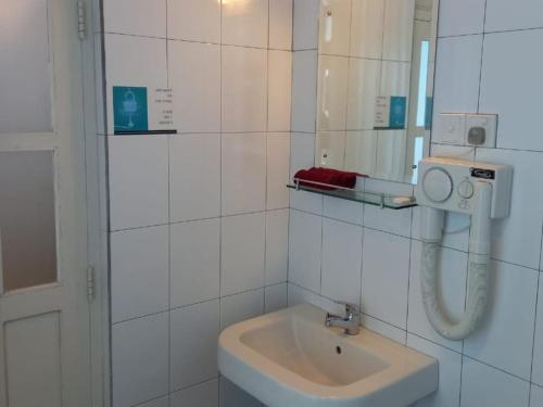 a white bathroom with a sink and a mirror at Forest Edge Hotel in Ginigathena