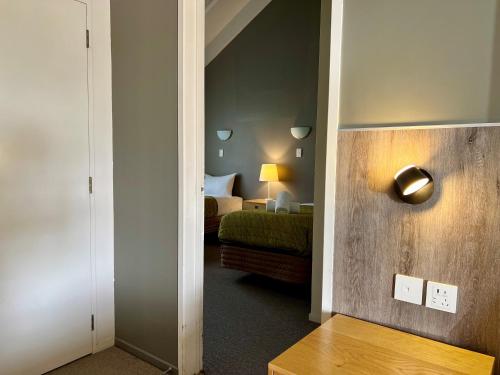 a room with a bedroom with a bed and a lightswitch at Airport Manor Inn in Auckland