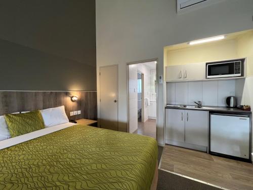 a hotel room with a bed and a kitchen at Airport Manor Inn in Auckland